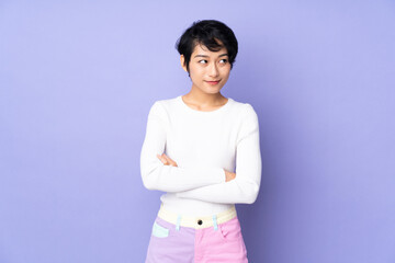 Young Vietnamese woman with short hair over isolated purple background having doubts while looking side