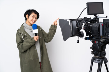 Reporter Vietnamese woman holding a microphone and reporting news pointing finger to the side and presenting a product