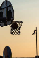Basketball through hoop in golden sunset light.