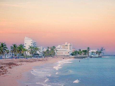 San Juan, Puerto Rico. January 2021. People is resting on San Juan's Ocean Park Beach after a day's work just before sunset.