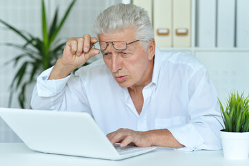 Close up portrait of surprised senior man looking at laptop