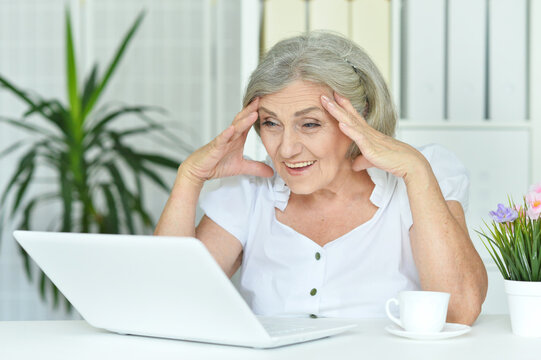 Close up portrait of happy senior woman using laptop