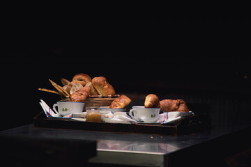 Traditional French breakfast display with croissants, pastry, tea, and coffee