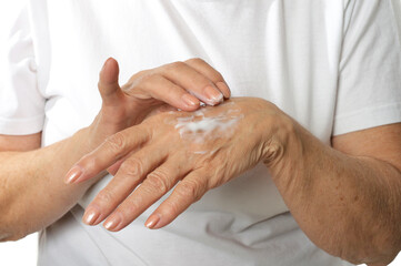 Older woman applying cream on hands closeup