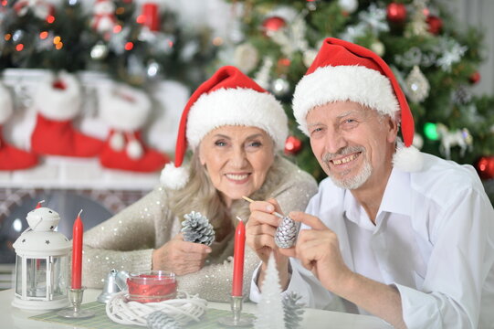 Happy senior couple in Santa hats preparing for Christmas or New Year