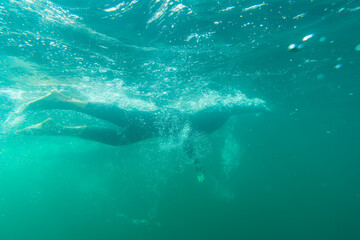 Fototapeta na wymiar Athlete in a wetsuit swims in a lake