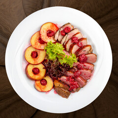 Duck breast mangre with berry confit and baked apple.  On a wooden background