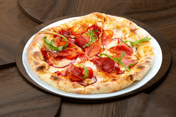 Pizza with Parma ham and cherry tomatoes. On a wooden background