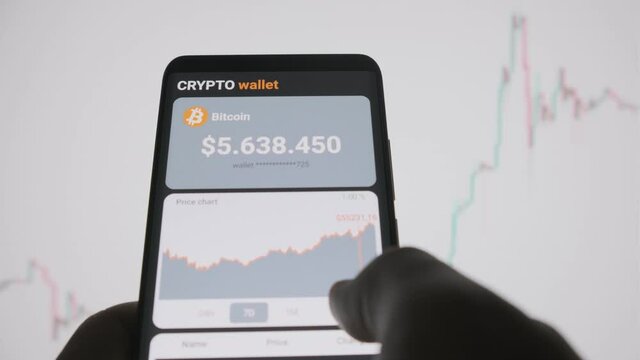 Smartphone with mobile application cryptocurrency wallet. A man analyzes the price chart for bitcoin in a mobile application and buys bitcoins. The concept of cryptocurrency  trading 