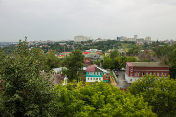 Fototapeta na wymiar VLADIMIR, RUSSIA-AUGUST, 11, 2021: panoramic top view of the roofs of the historic buildings of the old city and the lush green foliage of trees on a cloudy summer day