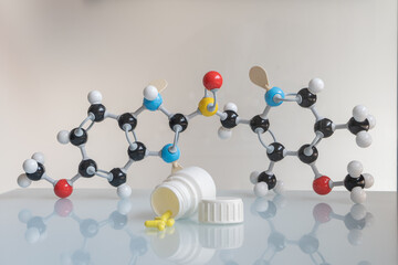Omeprazole pills and pill bote with omeprazole chemical formula made by molecular model in the...