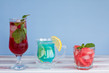 three types of different fruit and berry drinks. Cherry, watermelon red and blue with lemon alcoholic and non-alcoholic cocktails in summer