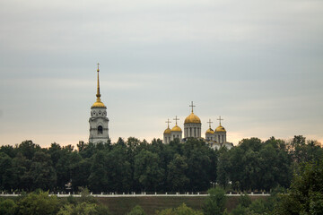 Fototapeta na wymiar panoramic top view of the old city with historical architecture and the Assumption Cathedral among the green foliage of trees and a cloudy summer day and copy space in Vladimir Russia