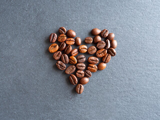 heart shape made of roasted coffee beans, flat lay top view coffee on dark slate background, sustainability concept