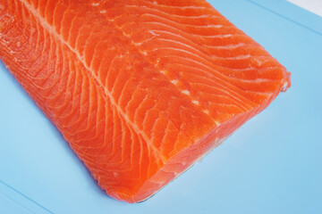 Fillet of red fish on a blue plastic cutting board.