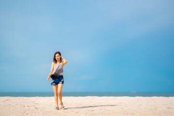 Fototapeta na wymiar Portrait beautiful Asian woman walking at tropical beach and blue sky