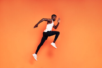 Fototapeta na wymiar Male runner doing fitness workout. Athlete exercising over an orange background.