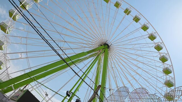 Noria atracci&oacute;n de feria de d&iacute;a con cielo de color azul.