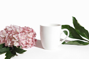 mockup tea mug, white cup for tea or coffee. template for your design. white background with pink flowers and green leaves.