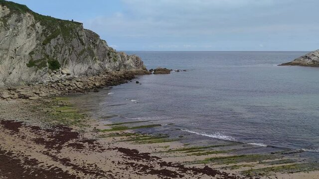 Playa de Covachos durante la marea baja e isla del Castro unida a la costa por un t&oacute;mbolo de arena en Cantabria, Espa&ntilde;a