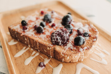 MIxed berries toast bread with condensed milk on wooden plate.