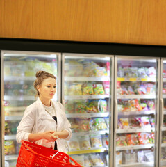 Woman choosing frozen food from a supermarket freezer