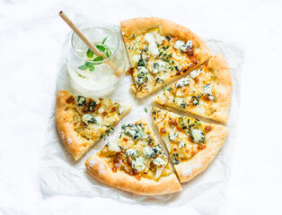 Gorgonzola pears thyme crispy pizza and a glass of white wine on a light background, top view