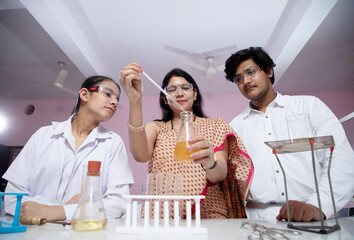 low angle shot of Teacher and student performing experiment in Chemistry lab
