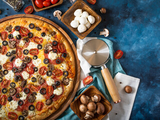 Traditional Italian pizza, many ingredients, knife on a blue background. View from above. High angle view. Restaurant, hotel, pizzeria, fast food.