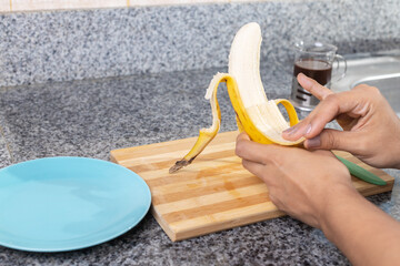 opening banana to chop on table in kitchen