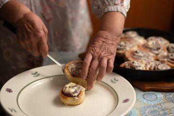 Hands and buns close-up.happy old woman Granny cooks in kitchen cinnamon rolls and bakes cookies. Portrait, selective focus, low key