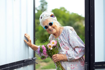An elderly woman comes to visit with a smile. Portrait of a happy grandmother with a bouquet of...