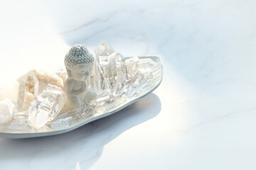 Fototapeta na wymiar Clear quartz minerals and little Buddha statue on white background. Magic gemstones crystals for healing esoteric spiritual practice, relaxation and meditation. life balance. Home decor in interior