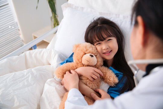 smiling girl with teddy bear in the hospital bed