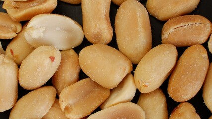 Lots of salted peanuts on dark background as close-up