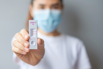 woman holding Rapid Antigen Test kit with Positive result during swab COVID-19 testing. Coronavirus...