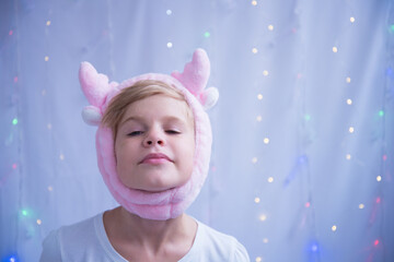 The child is fooling around. A girl posing in a New Year's hat in the form of deer horns. Preparing...