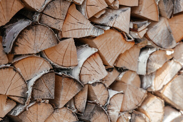 Fototapeta premium Pile of firewood toned texture background. Preparation of firewood for the winter for cooking, kindling of a fireplace. Stacks of firewood in the forest in the yard in warm morning evening sun light.