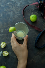 Limes and cocktail with hand  on black background.Dark moody concept