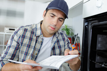technician with home appliances reading instructions