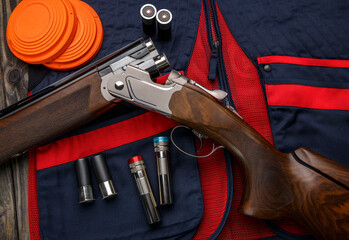 Double-barreled vertical shotgun and cartridges for it on a sports shooting vest. Shooting sport...