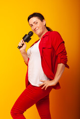 Woman with a microphone on a yellow background. The singer sings, Vocal lessons at school. The teacher is teaching.