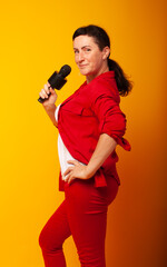Woman with a microphone on a yellow background. The singer sings, Vocal lessons at school. The teacher is teaching.