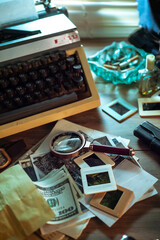 Private detective's desk, noir still life with a vintage phone, typewriter, lamp, gun and retro photos