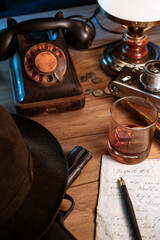 Private detective's desk, noir still life with a vintage phone, typewriter, lamp, gun and retro...