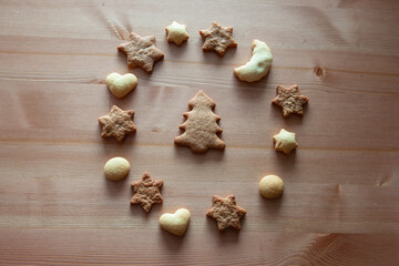 Christmas cookies, star figures, heart figures, moon figure, and Christmas tree is in the center. Different figures of ginger biscuits on a wood table