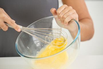 female chef beating eggs with wire whisk in bowl