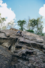 A little boy is engaged in mountaineering. The boy climbs the rock on a rope. Climbing training. Children's mountaineering.