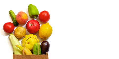 A paper shopping bag with vegetables and fruits, tomato, cucumber, squash, pepper, lemon, eggplant, zucchini, banana, apple, peach on white background