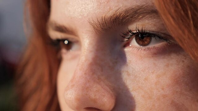 Close up of woman's face. Attractive girl opening her beautiful brown eyes. Caucasian young female model with beautiful eyes looking at camera. Slow-motion, macro extreme close-up, 4K.